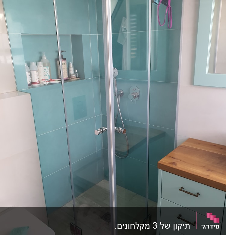 מקלחון זכוכית עם מוצרי טיפוח על מדף